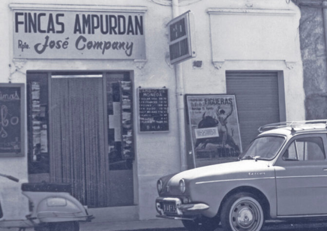 Fotografia antiga d'un local comercial amb el rètol Fincas Ampurdan - Rpte. José Company